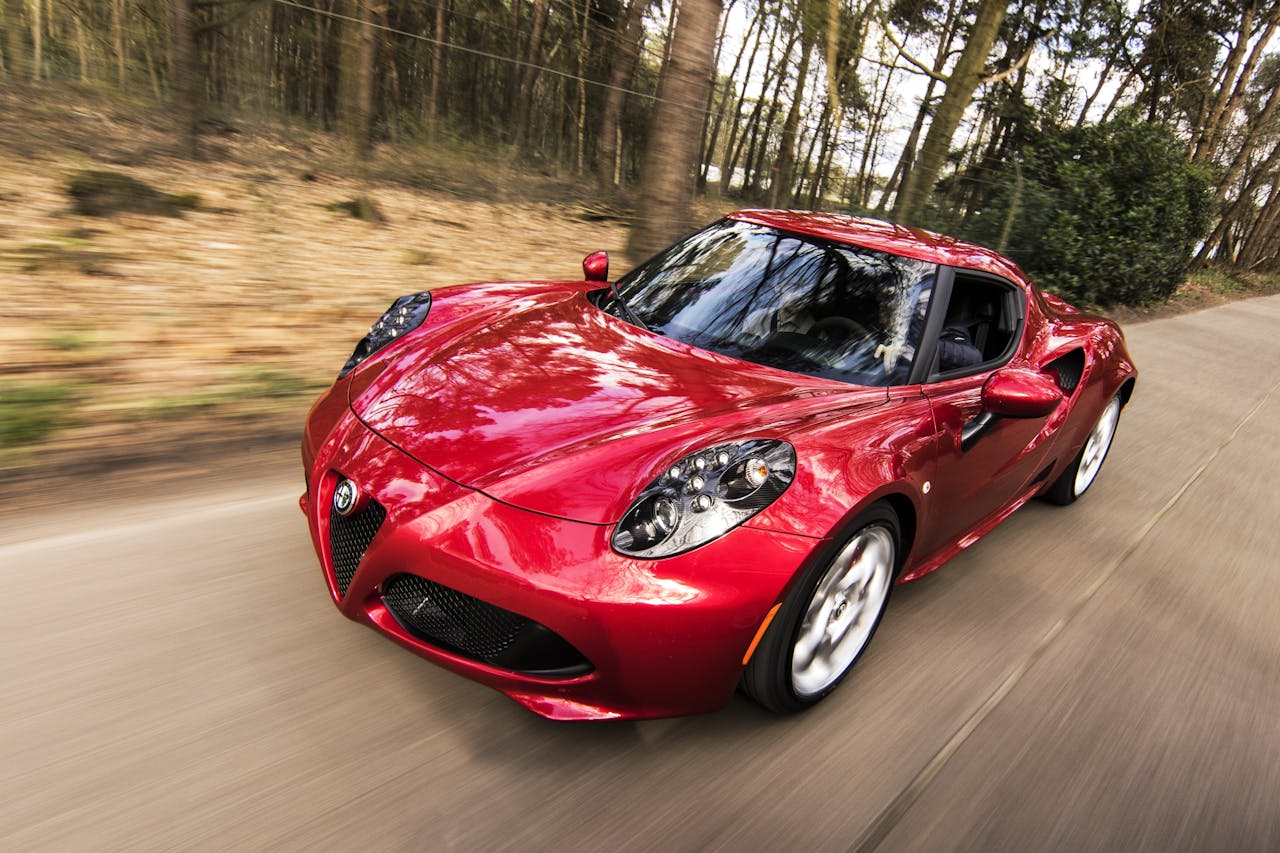 about-us A sleek red sports car driving fast on a forest road, showcasing speed and luxury.