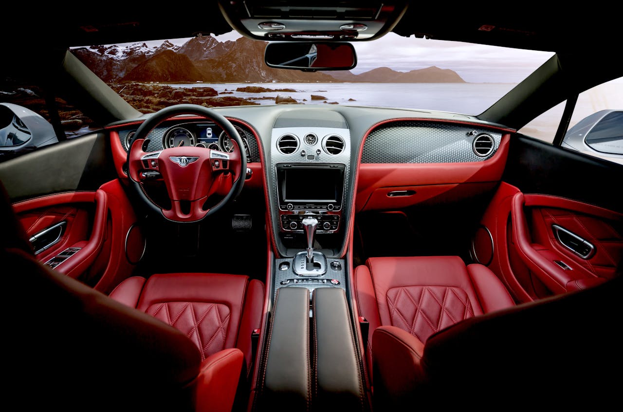 heros-img Red leather luxury sports car interior with mountain backdrop outside the window.